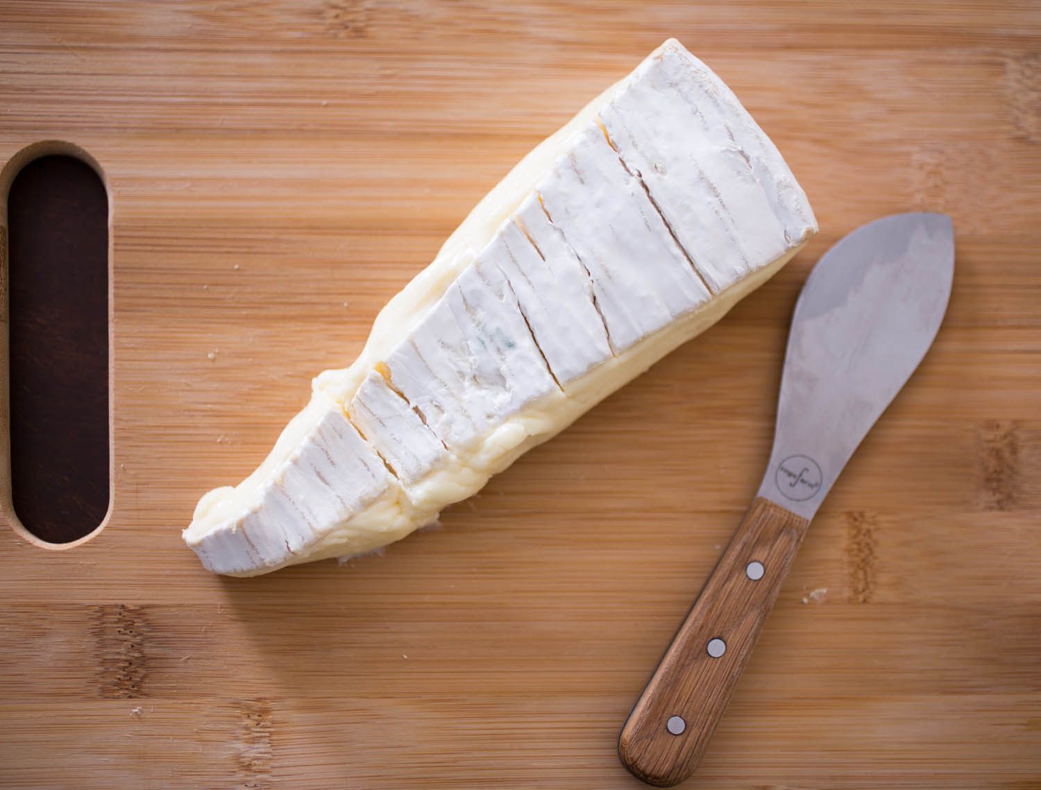 Overhead shot of an oozy wedge of Brie de Meaux on a cutting board.