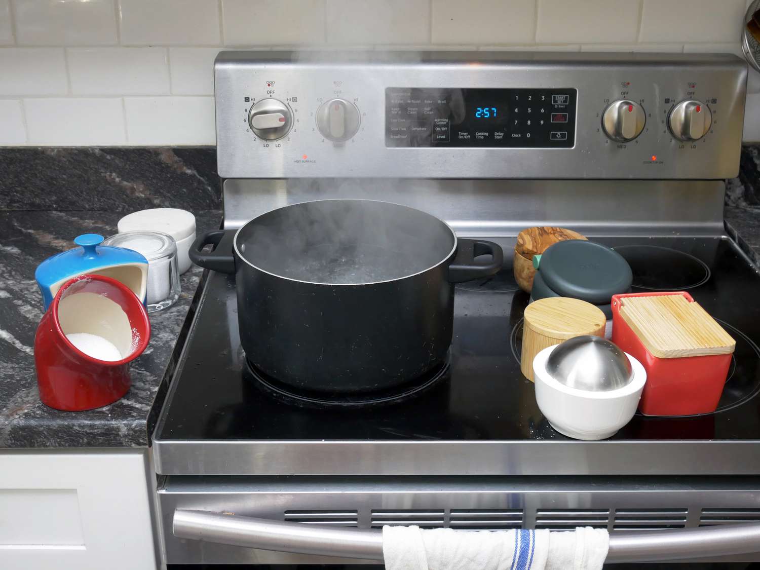 a pot of boiling water on a stove with salt cellars flanking each side
