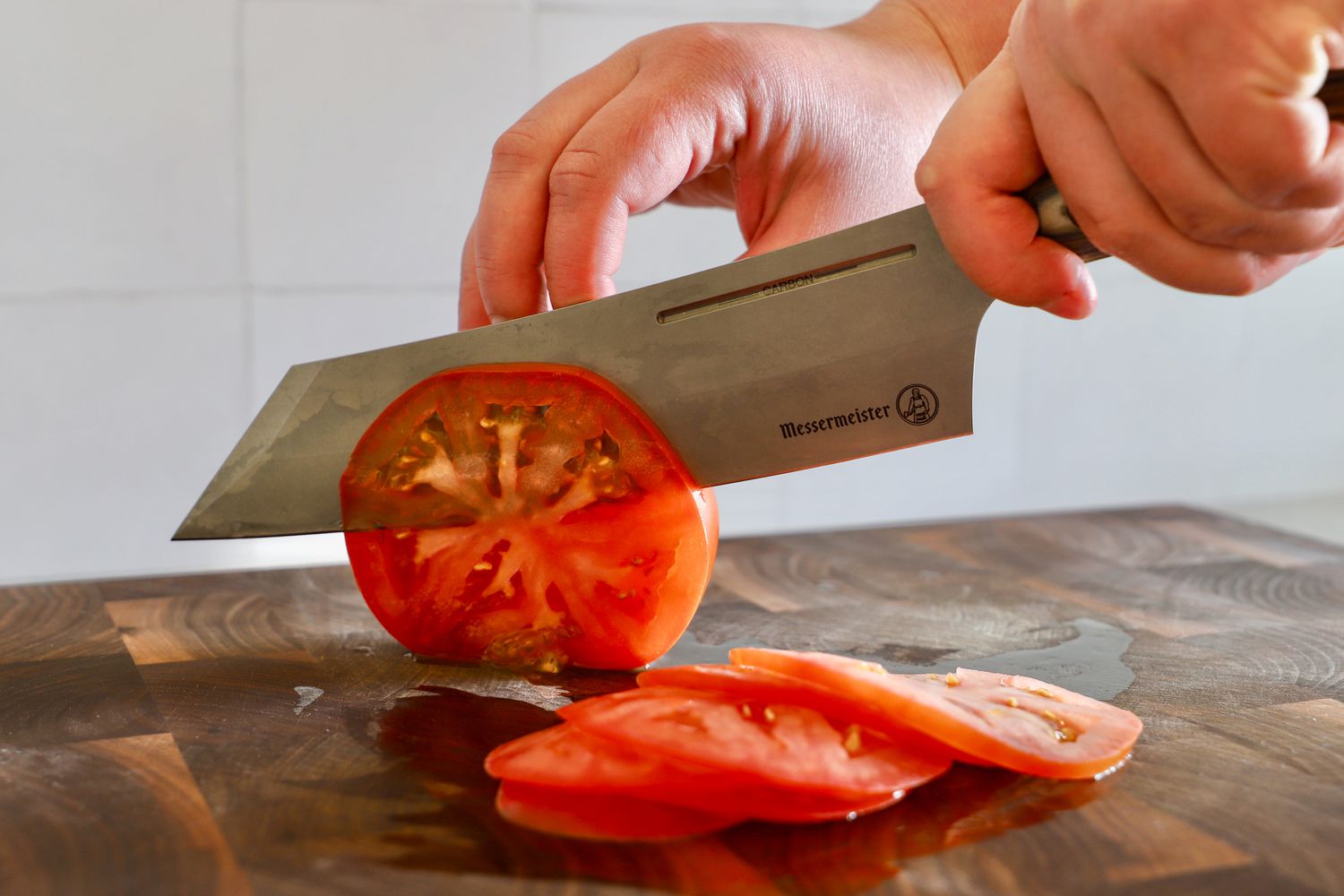 Messermeister Carbon 8 Inch Bunka Chef's Knife being used to slice a tomato