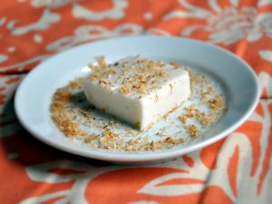 A square of haupia, served on a small plate and sprinkled with toasted coconut.