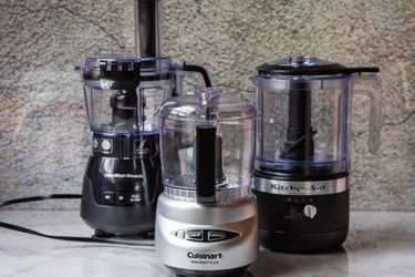 Three mini food processor on a marble kitchen countertop.