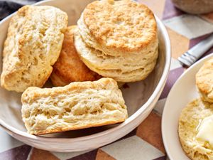 A bowl and plate containing freshly baked buttermilk biscuits