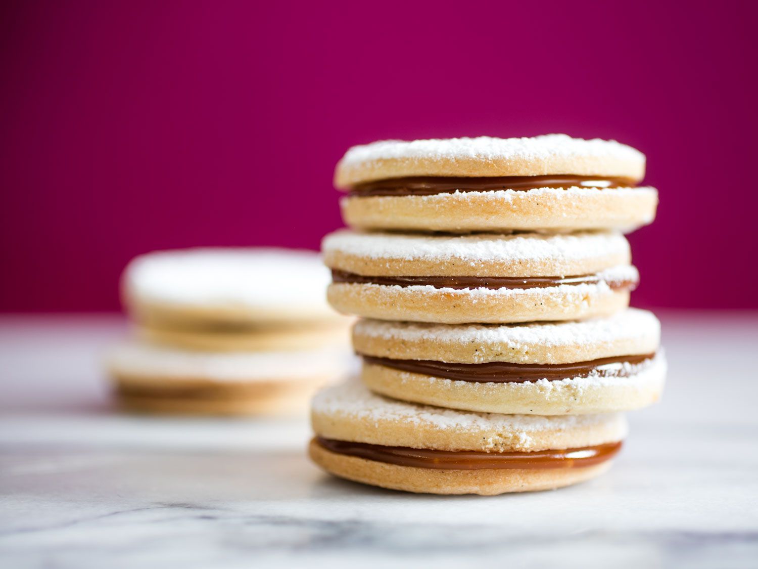 Close-up of a stack of alfajores. The cajeta filling of the alfajor on the bottom is bulging out.