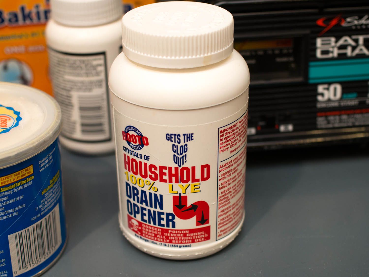 A bottle of Lye drain opener sitting with other products on a counter.