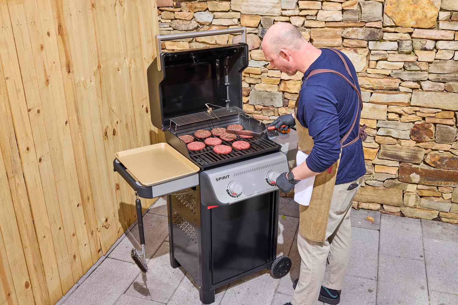 A person grilling patties on the Weber Spirit E-210 Gas Grill