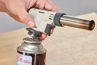 someone removing the iwatani torch from the butane