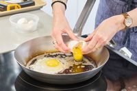 Eggs are cracked into the Vollrath 12.5 Inch French Style Carbon Steel Fry Pan
