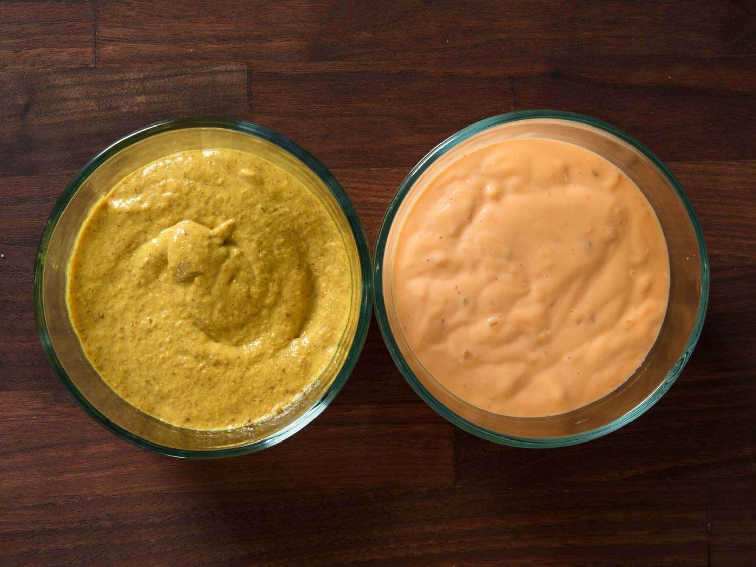 Yellow mustard and Russian dressing in two bowls.