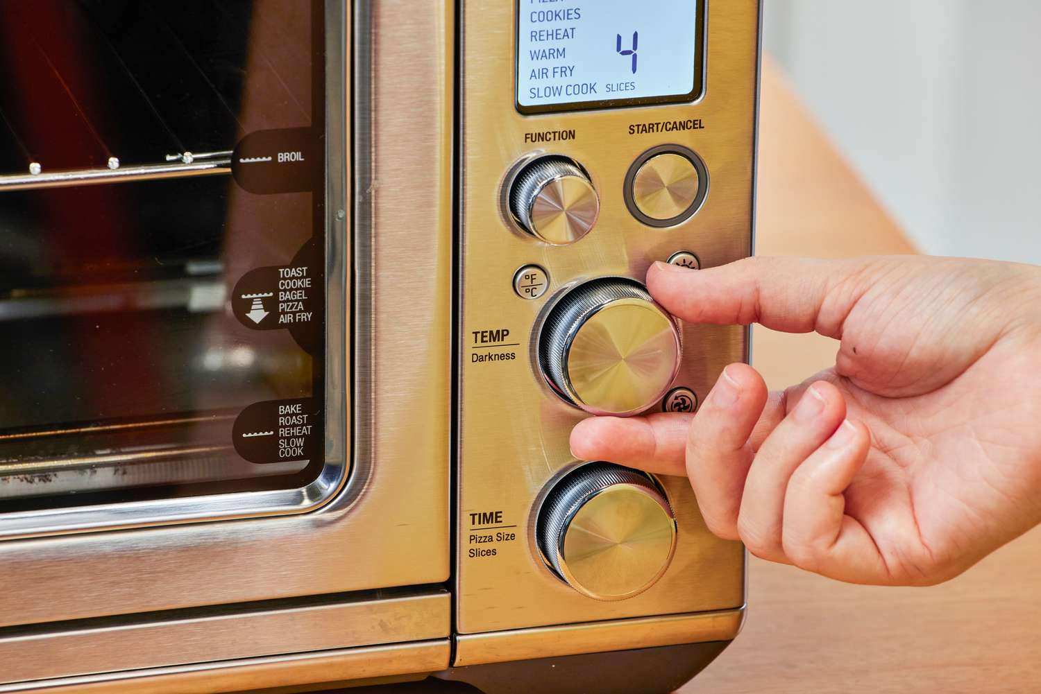 A hand turning a nob on the Breville the Smart Oven Air Fryer