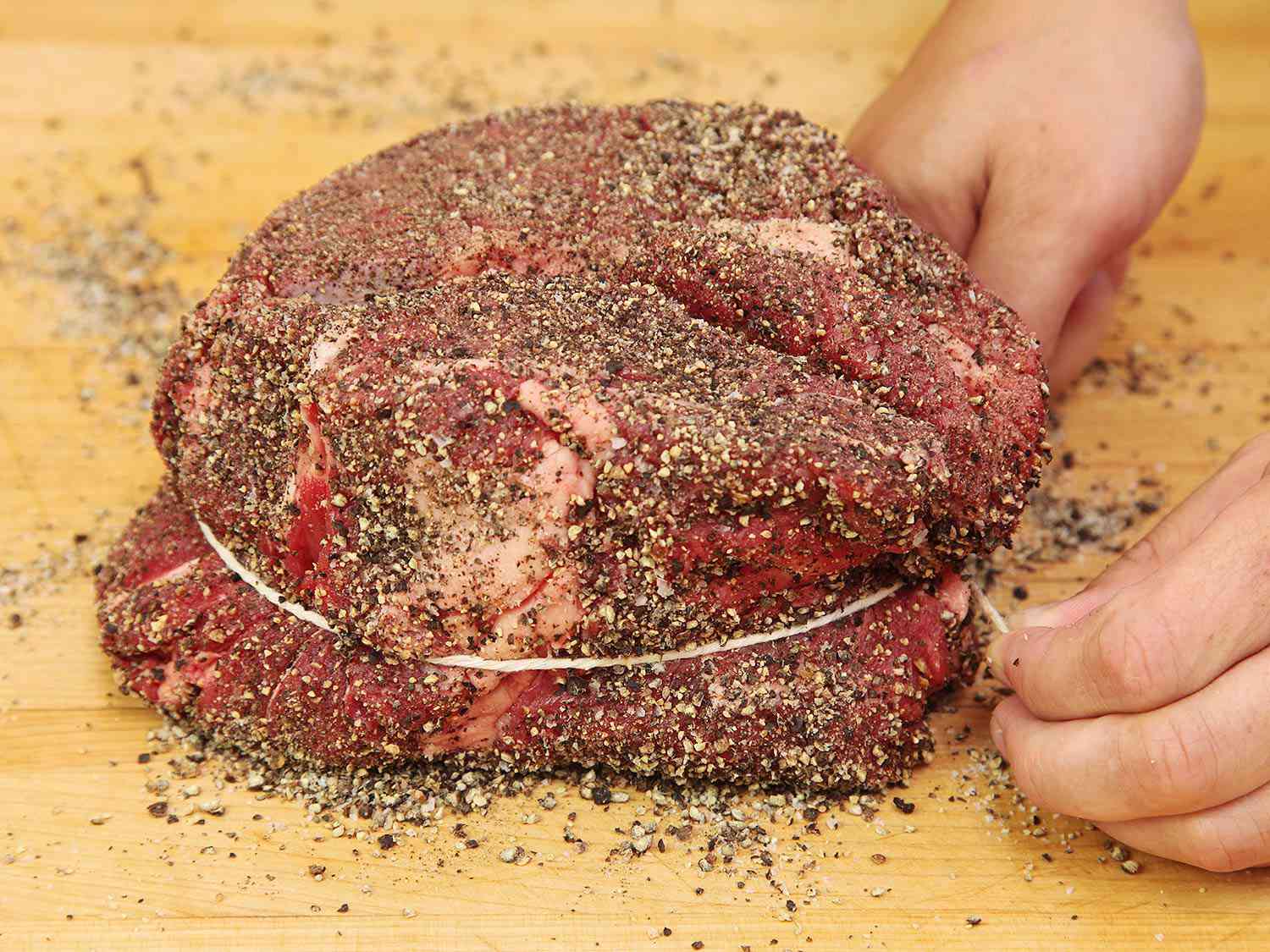 The seasoned chuck roast is tied with twine.