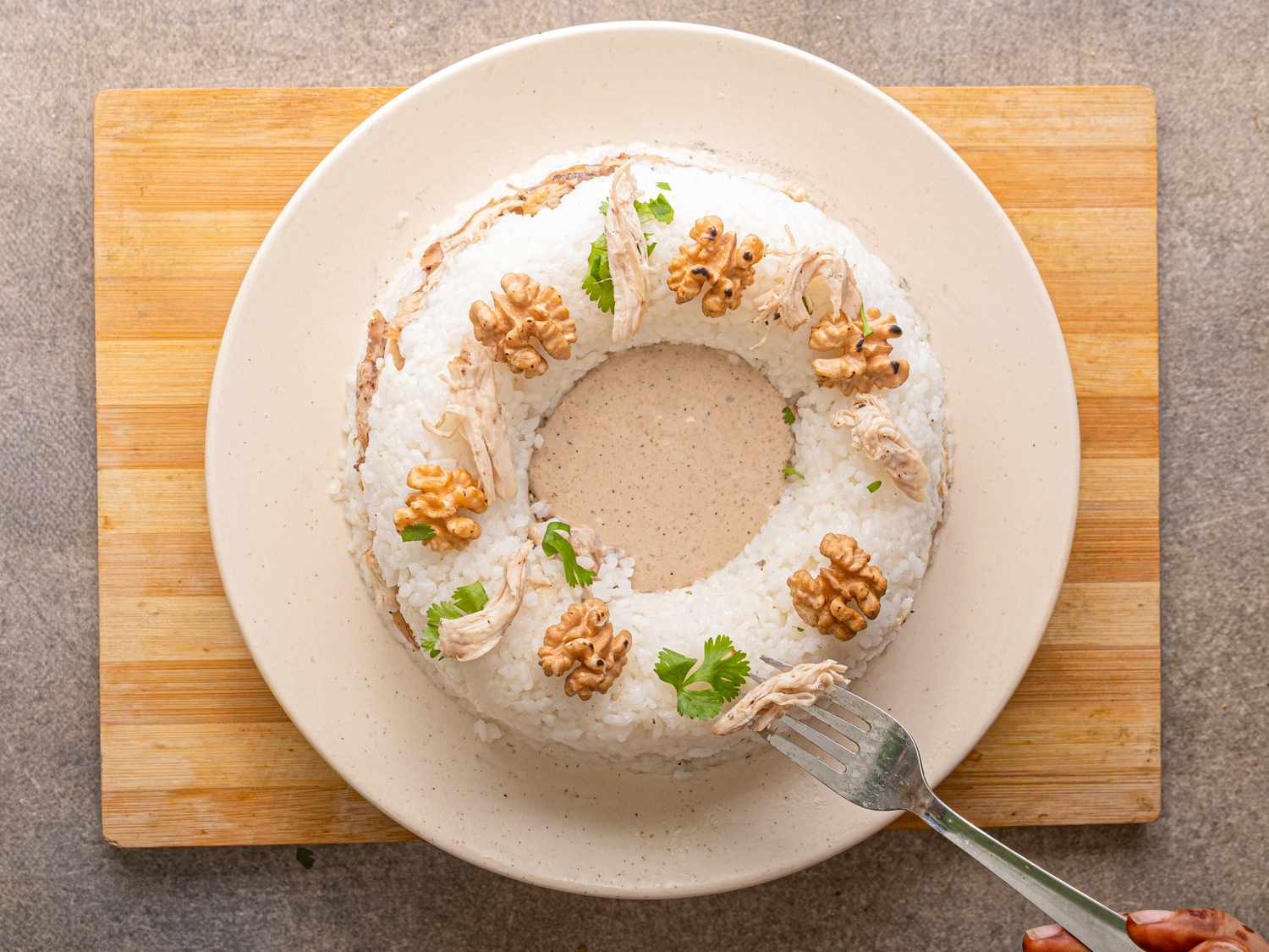 Plated Circassian chicken dish garnished with walnuts and herbs