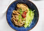 Sesame Noodles with chili paste, cucumbers, and scallions in a blue bow with a wavy patterm