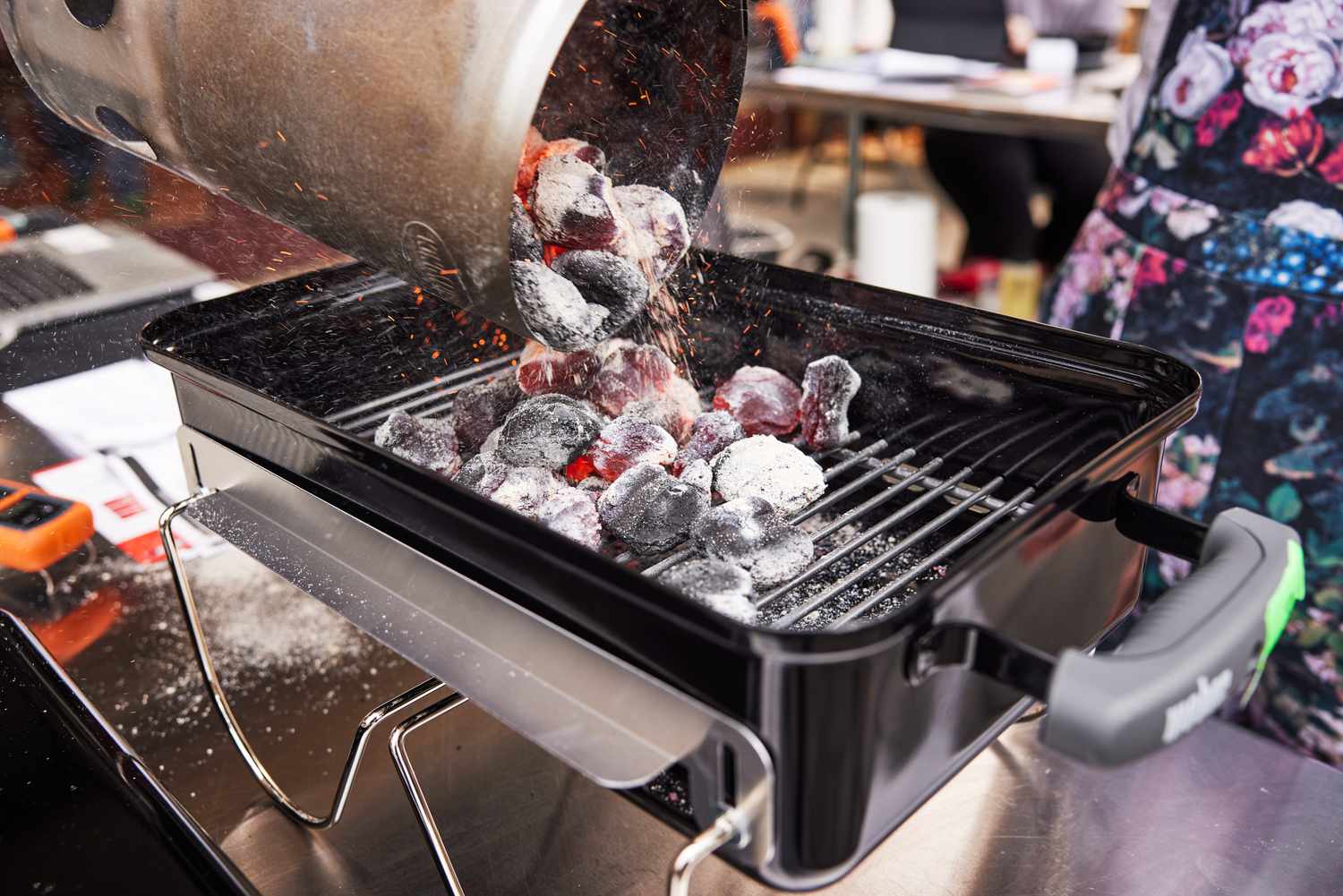 Hot charcoal briquettes poured onto a small grill.