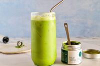 A glass of Matchaful Hikari Single Origin Matcha next to the container