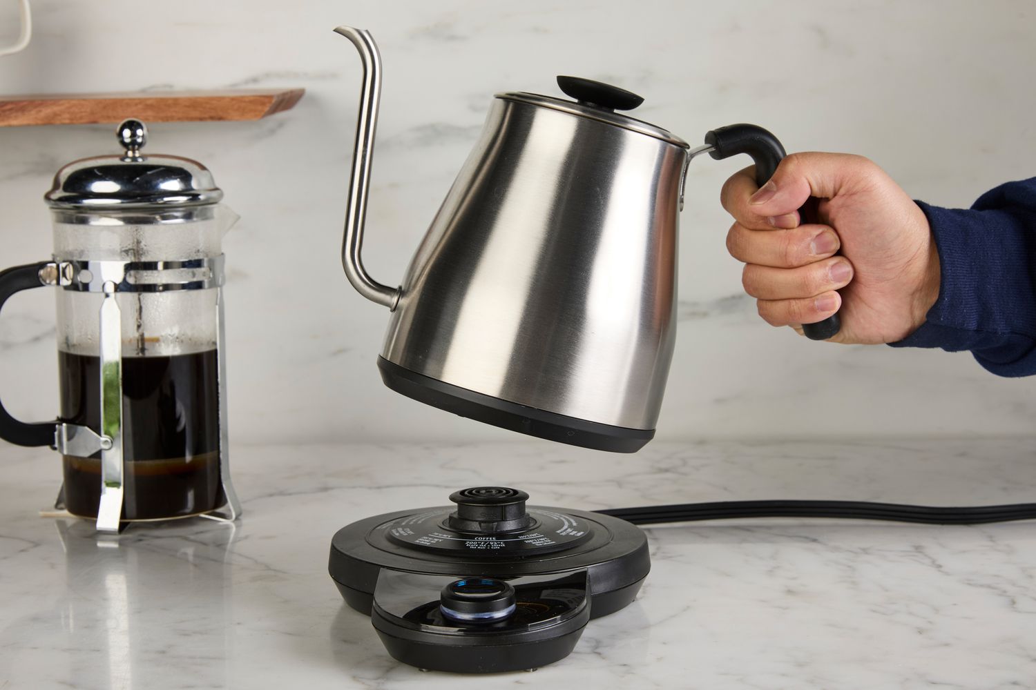 A person placing the OXO gooseneck kettle onto its base.
