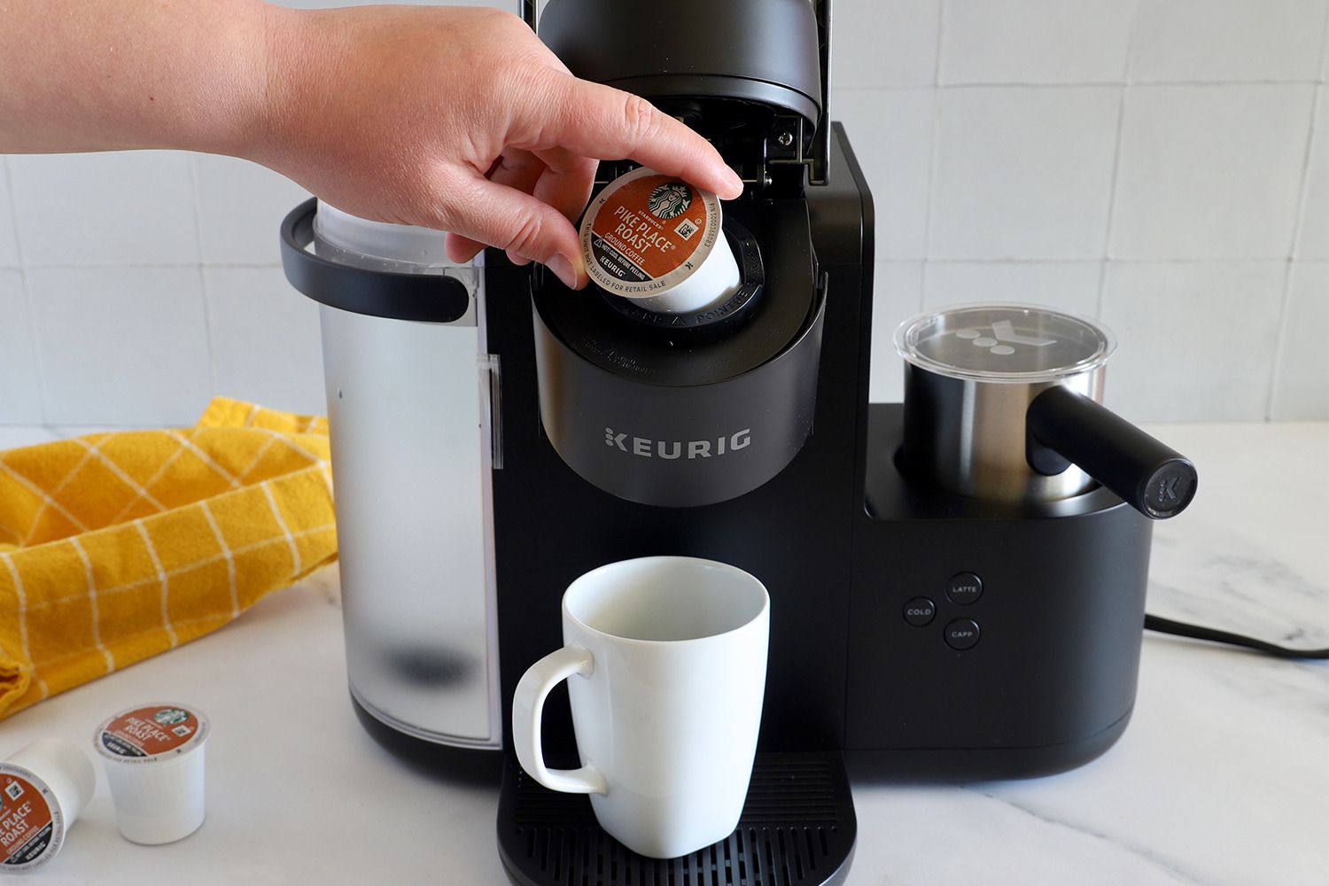 A person inserting a pod into a Keurig coffee maker.