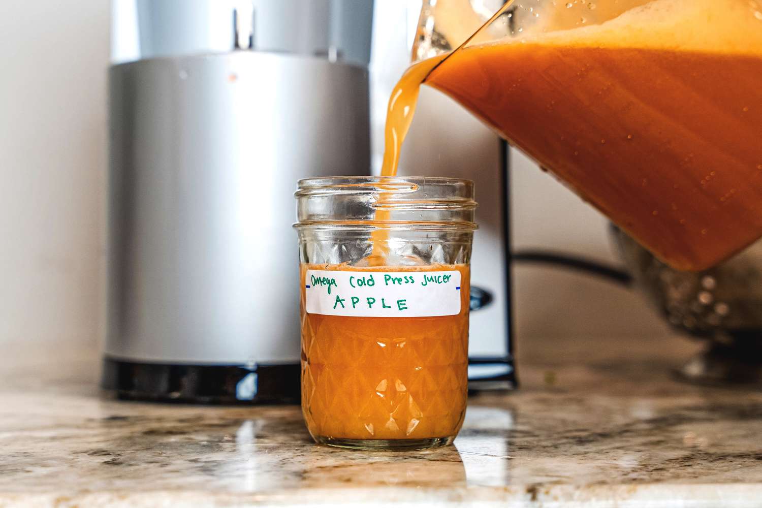 Apple juice being poured from the Omega juicer