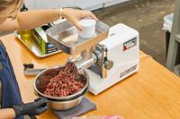 Person pushing meat in STX International Turboforce Classic 3000 Series Electric Meat Grinder & Sausage Stuffer