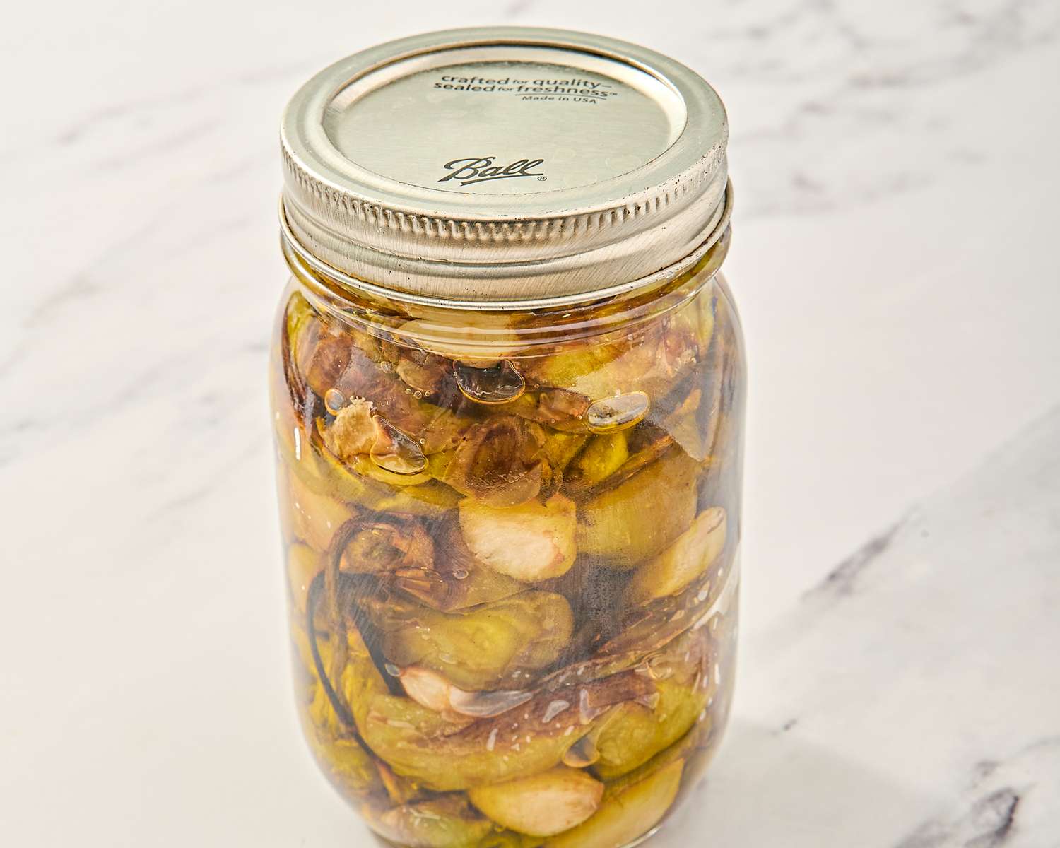 A jar containing preserved vegetables and seasonings sealed with a metal lid