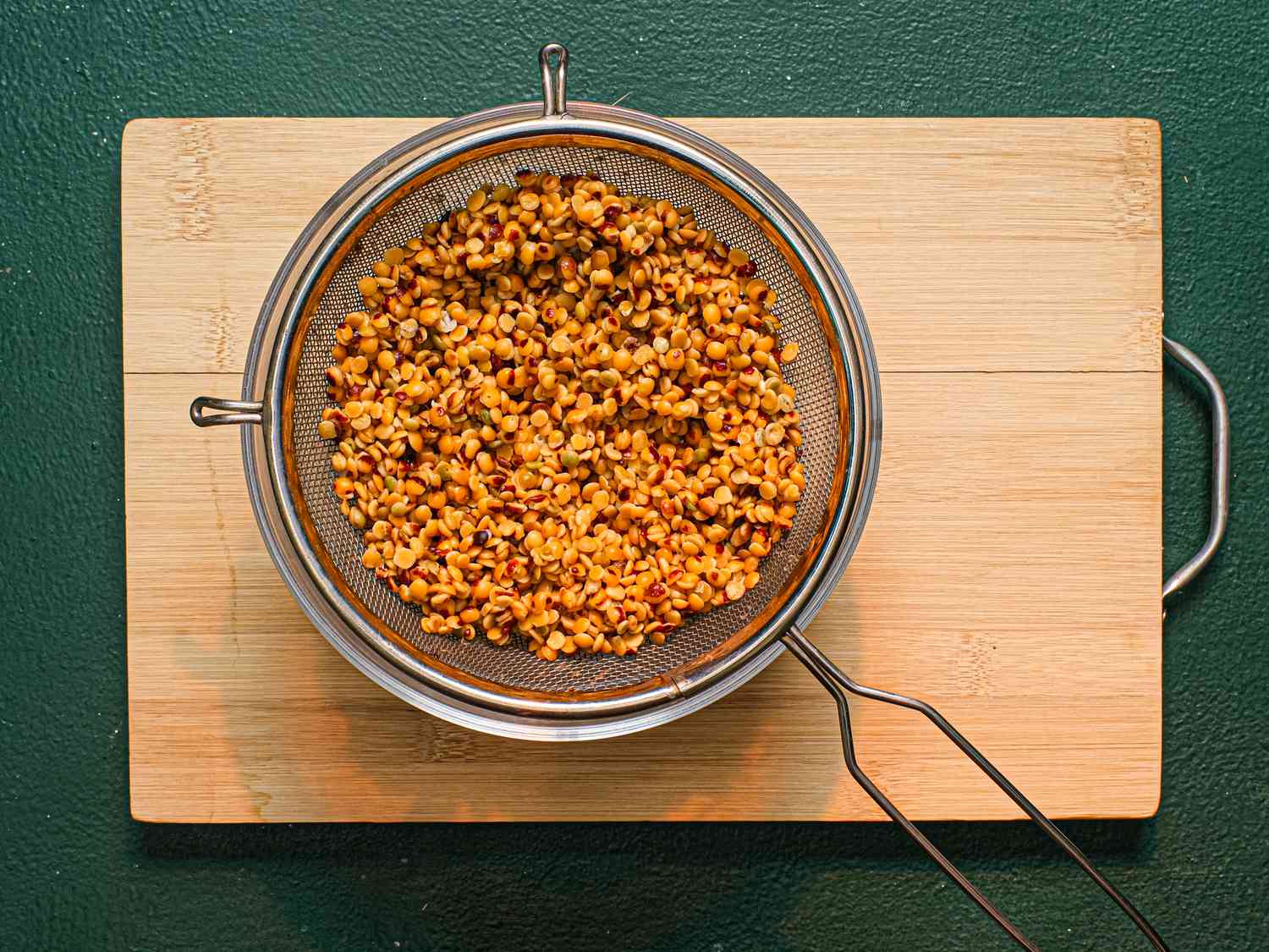 Toor dal (split pigeon peas) in a strainer set over a bowl.