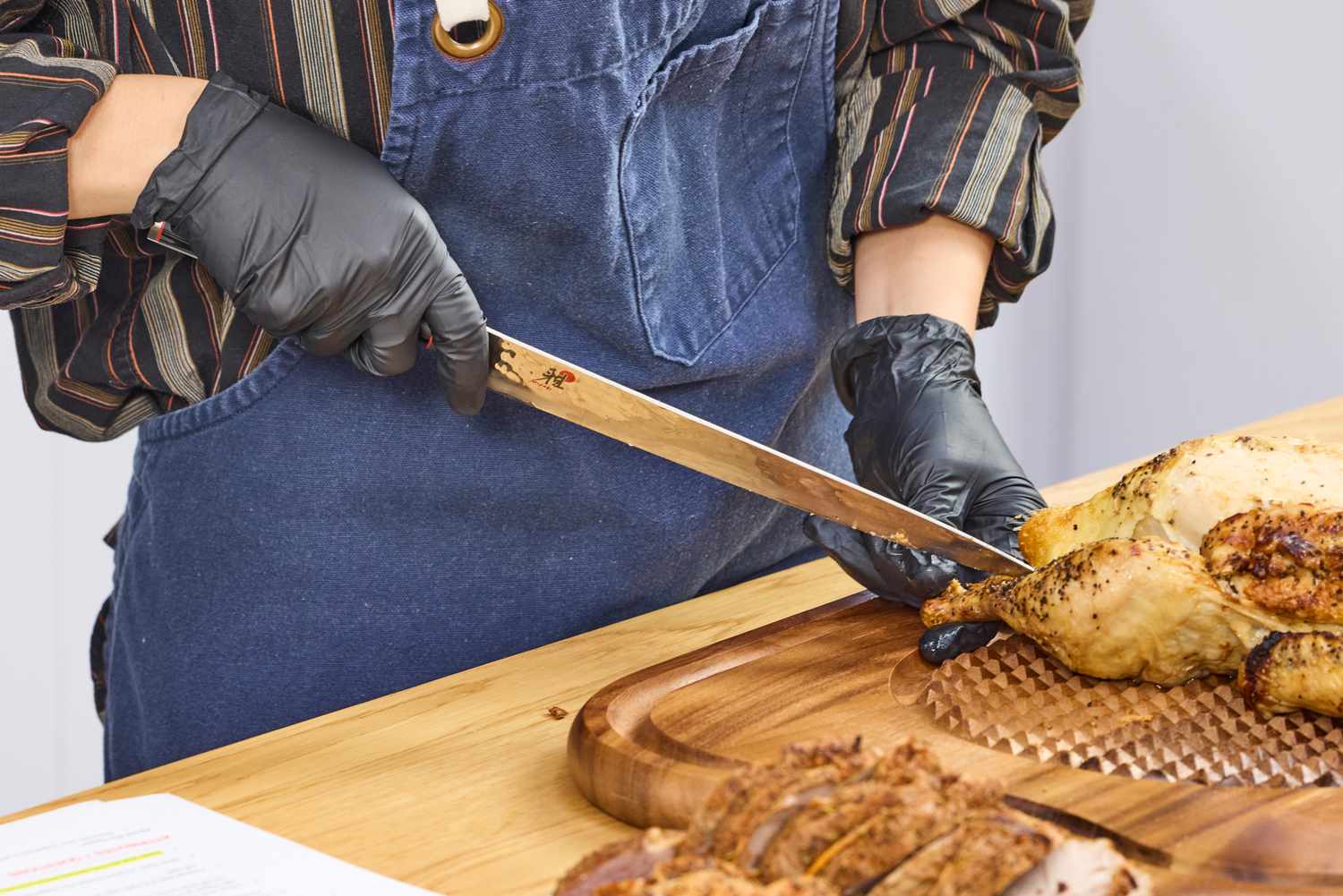 A person slices chicken with the Miyabi Mizu SG2 9.5 Inch Slicing Knife