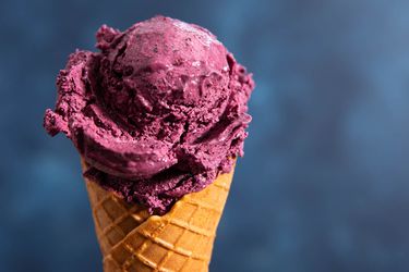 A scoop of no-churn blueberry ice cream on a waffle cone.