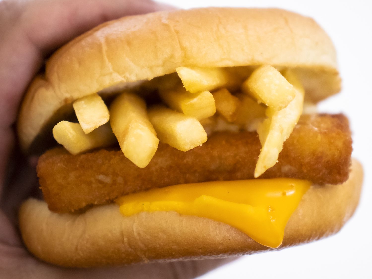 Hand gripping a McDonald's filet-o-fish with French fries slid inside -- don't do this!