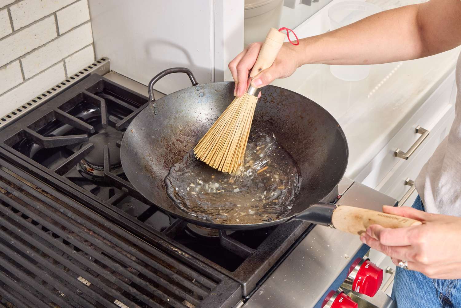 A person oils the bottom of the Mammafong Pre-Seasoned Blue Carbon Steel Flat-Bottom Pow Wok