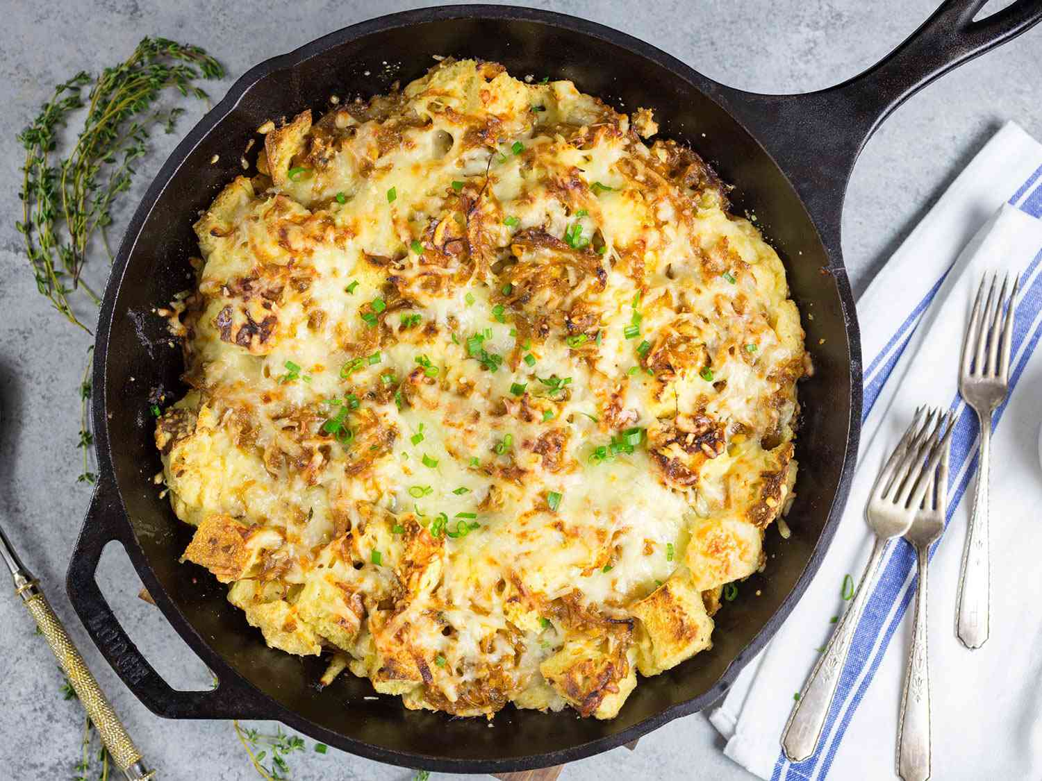 Overhead view of French onion strata, served in the cast iron skillet it was baked in.