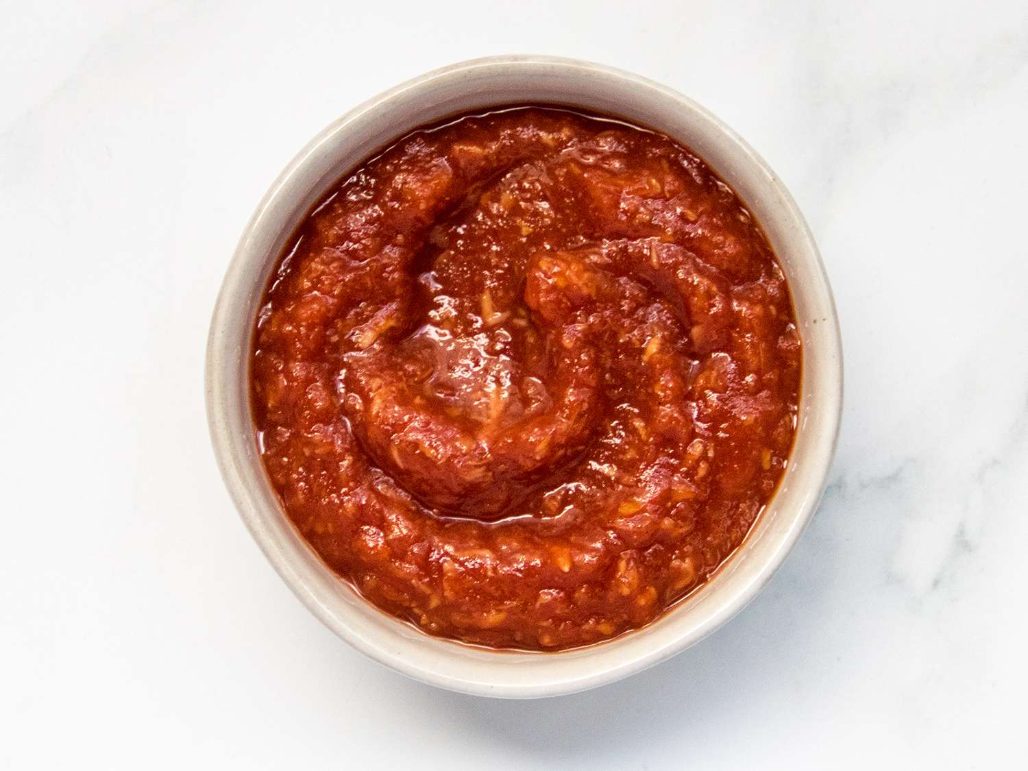 Cocktail sauce in a ceramic bowl on a stone background.