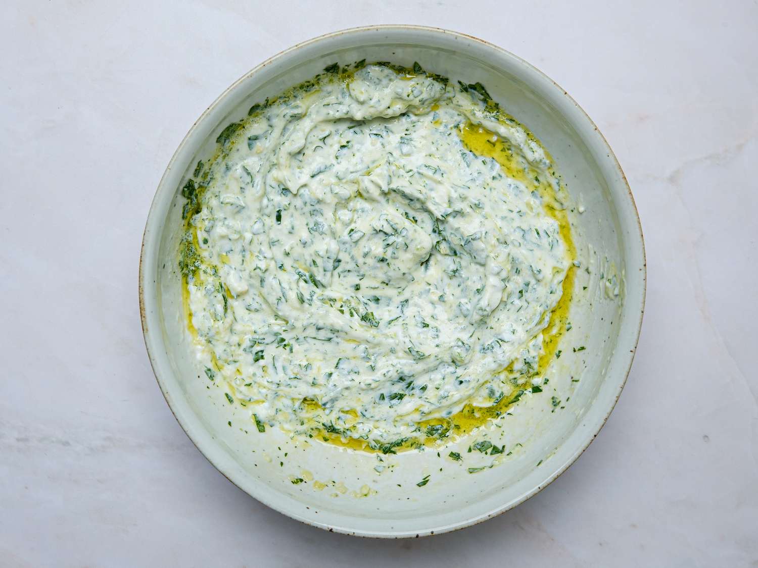 A bowl of creamy yogurtbased dip garnished with herbs and olive oil