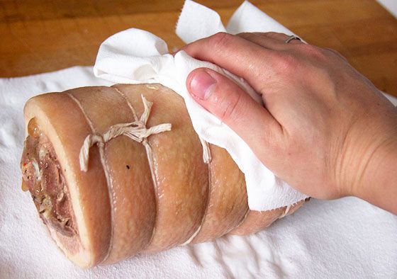 patting cooked pork belly roll dry with towel