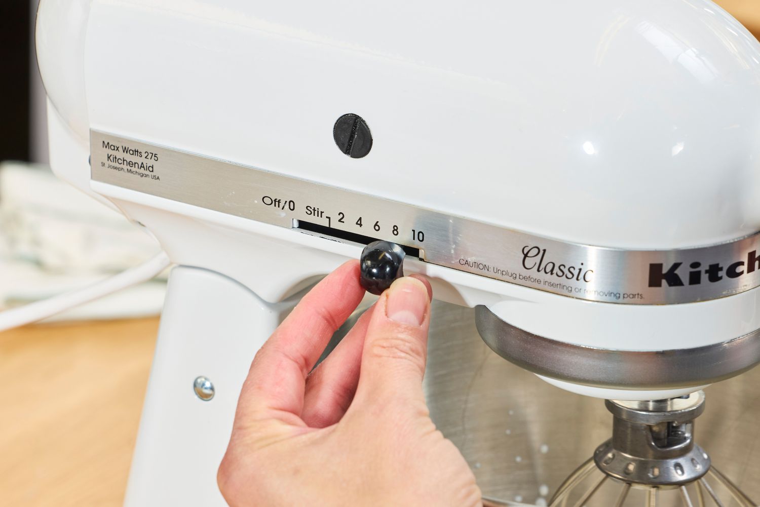 A person adjusts the speed on the KitchenAid Classic Plus Series 4.5 Quart Tilt-Head Stand Mixer