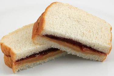 Peanut butter and jelly sandwich on white sliced bread, cut in half with the cut sides facing the camera. 