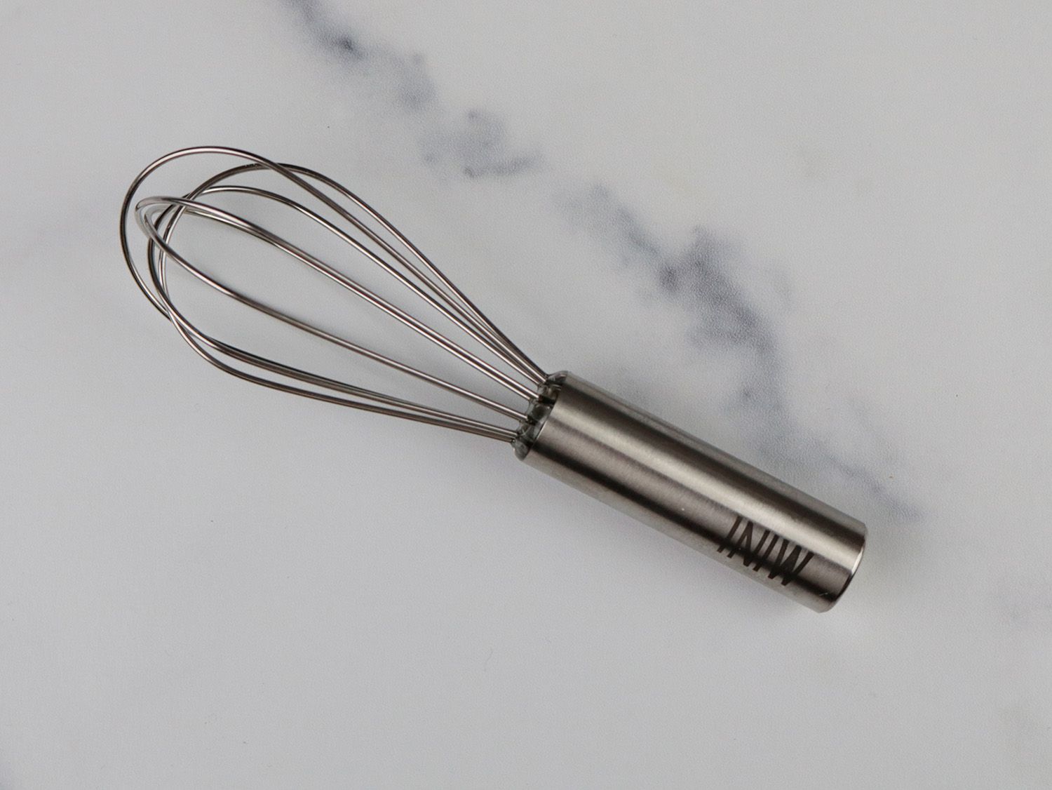 a mini balloon whisk against a marble surface