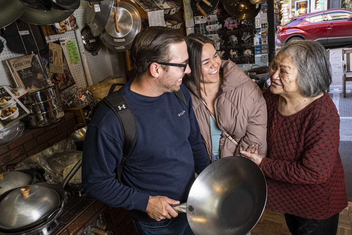 Tane Chan holding the arm of a customer who just purchased a wok