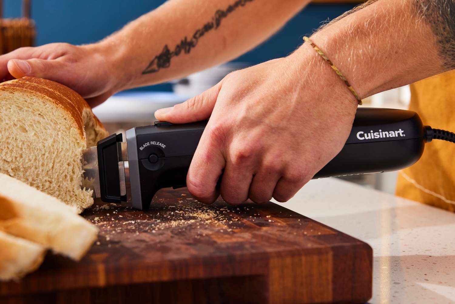 a person using the Cuisinart to slice bread with the finger guard hitting the wooden cutting board