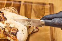 A person slices a chicken with the Mercer Culinary 10-Inch Carving Knife