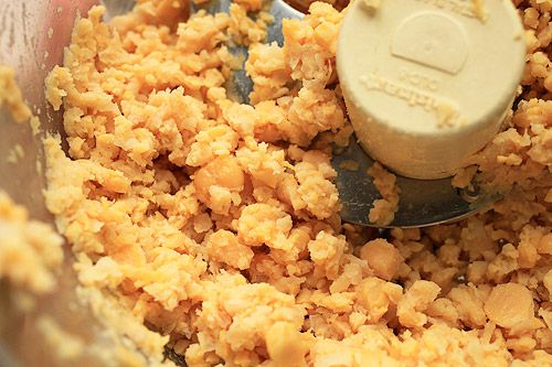 The inside of a food processor filled with partially processed chickpeas.