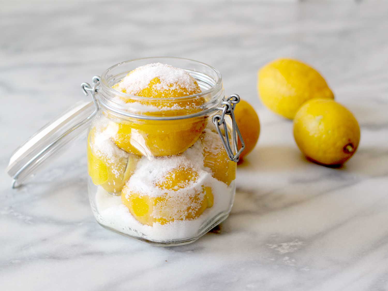 Lemons layered with salt for preserving in clamp-lid glass jar