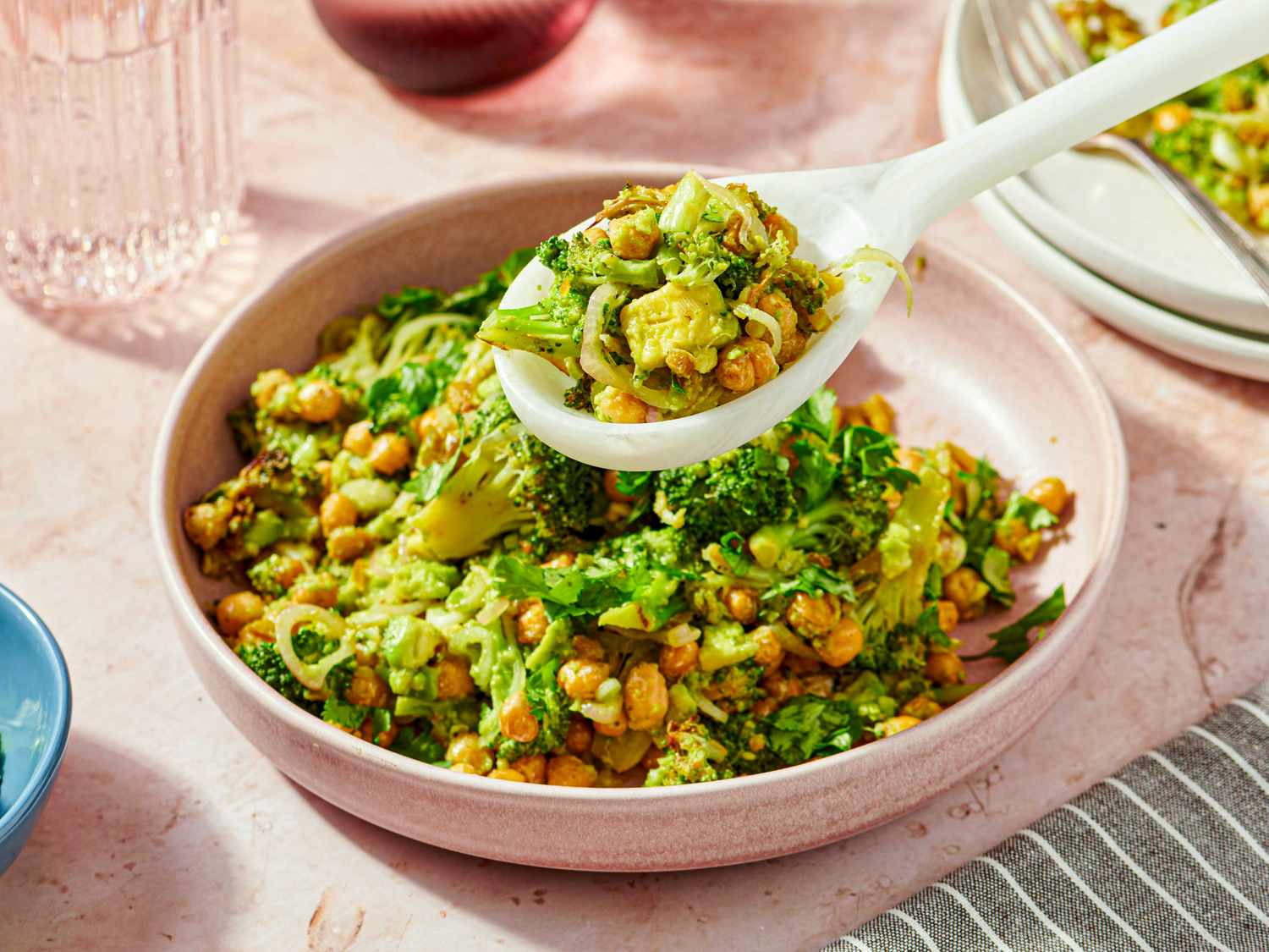 A bowl of broccoli and chickpea salad with a spoon serving a portion