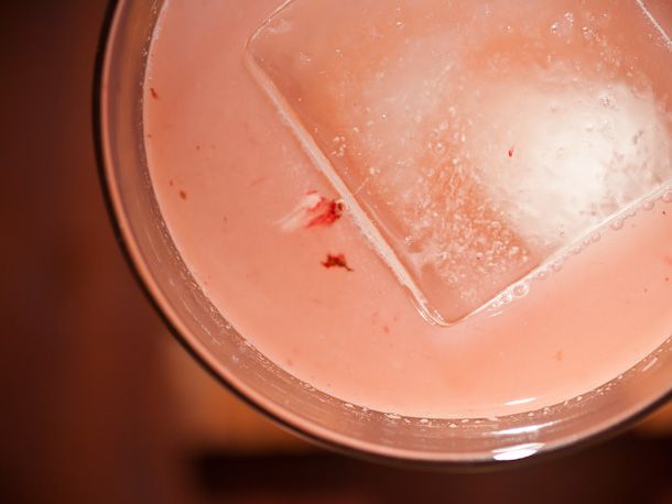 Overhead closeup of a Monkey See Monkey Do cocktail, served with a large ice cube.