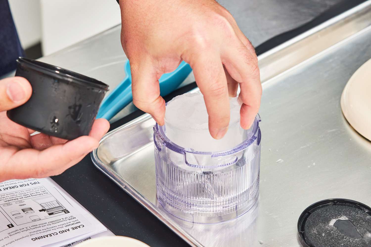 A person adding a puck of ice to a shaved ice machine.