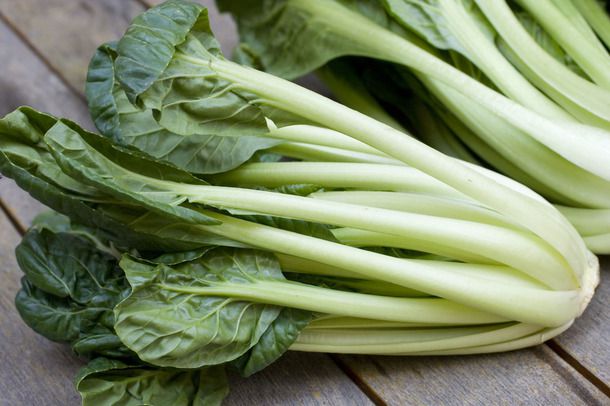 Tatsoi greens sitting on a wooden surface