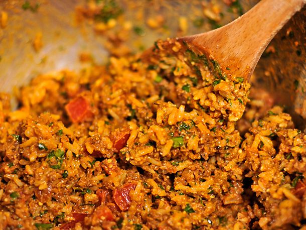 Mixing chorizo with rice, tomatoes, crema, cilantro, and Cotija cheese in a mixing bowl. 