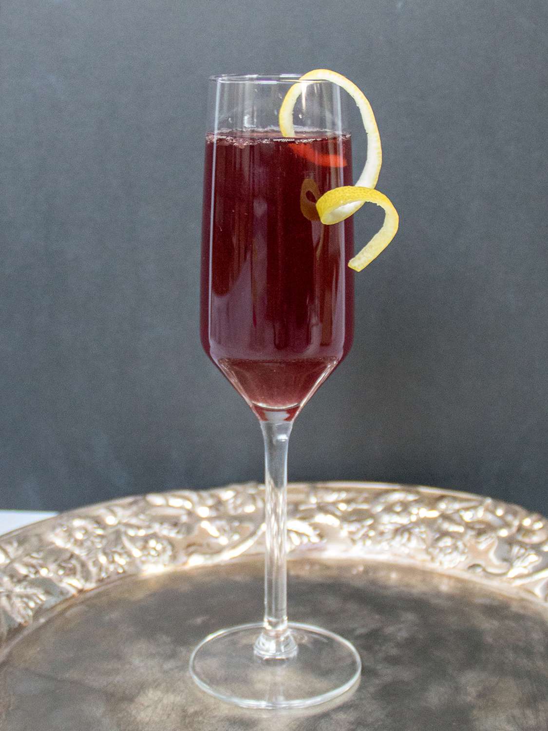 Pomegranate rouge in a Champagne flute with a citrus twist garnish on a serving platter