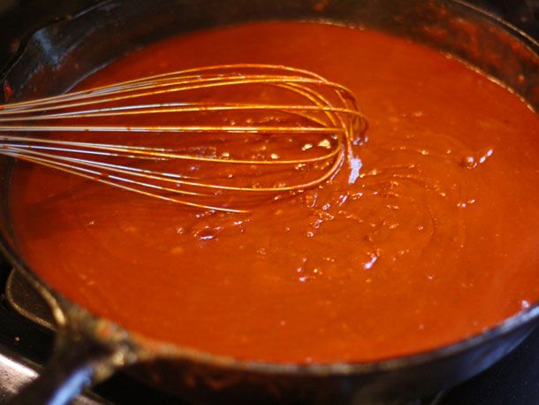 Whisking red chili gravy in a skillet.