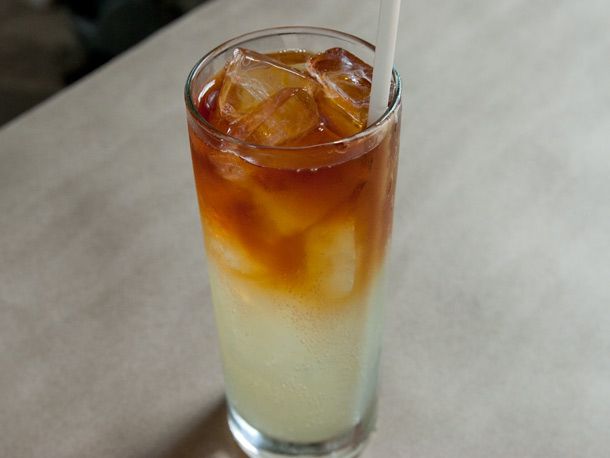 Dark and stormy cocktail in tall glass with straw.