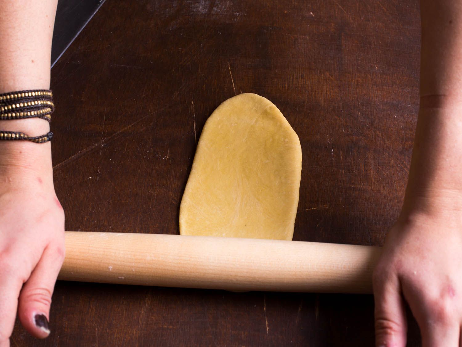 Rolling out a slab of pasta dough using a rolling pin. 
