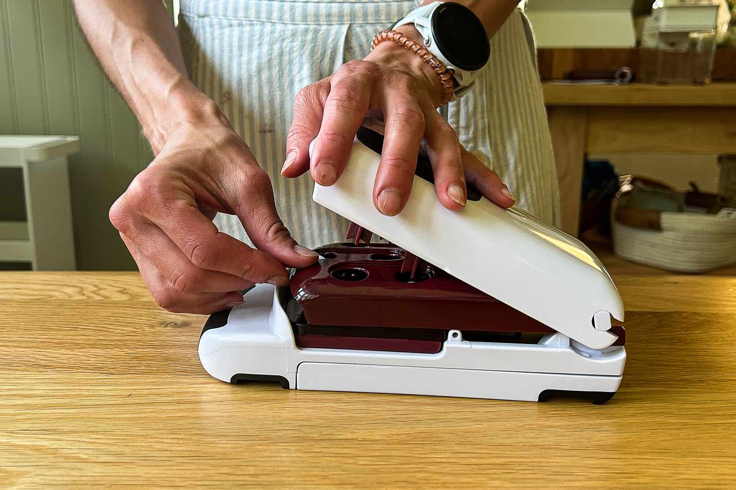 A person loading the OXO Good Grips Multi Cherry Pitter on a wooden surface
